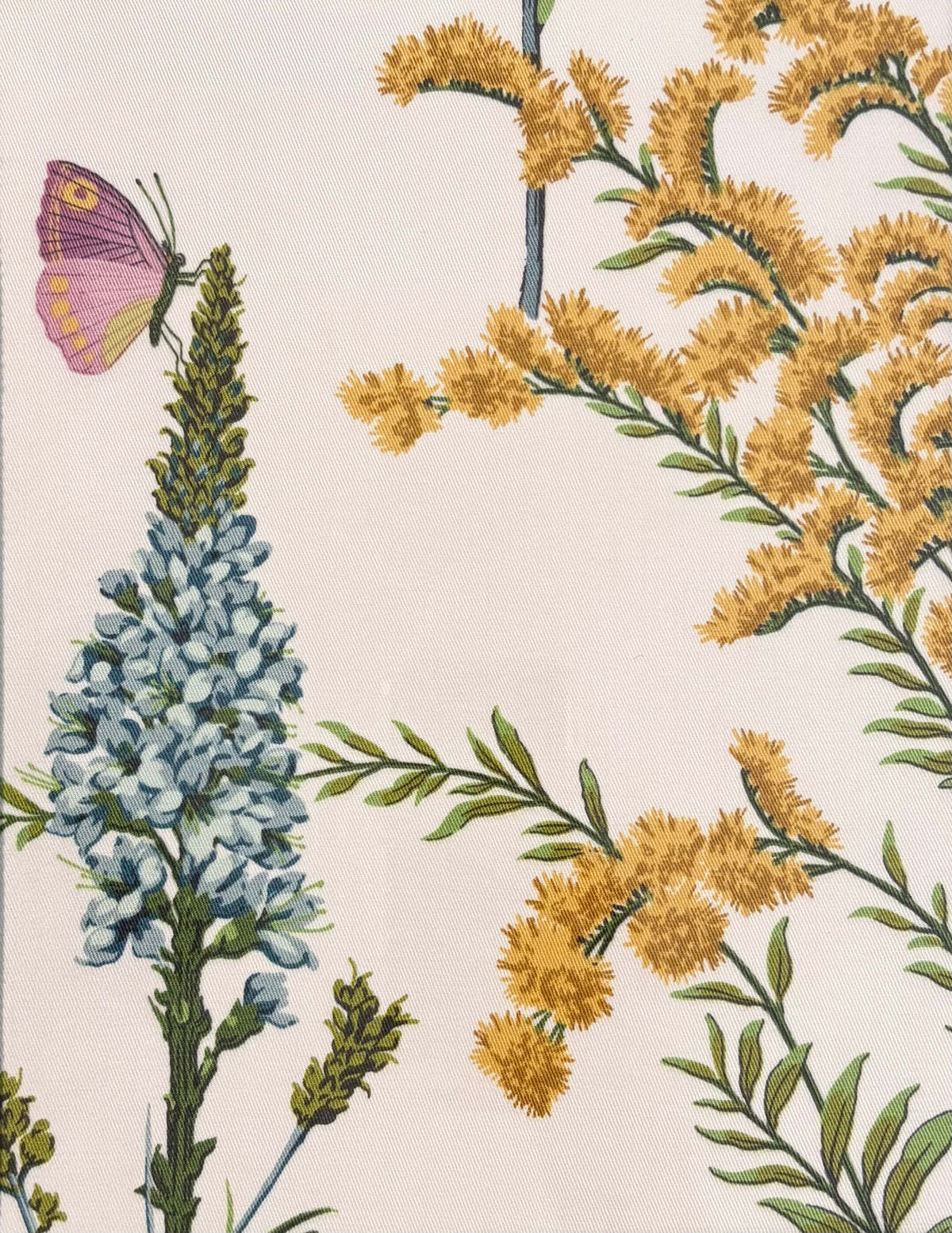 Close-up of the purple butterfly and blue flower spike beside yellow blossoms on cream Isabella fabric.