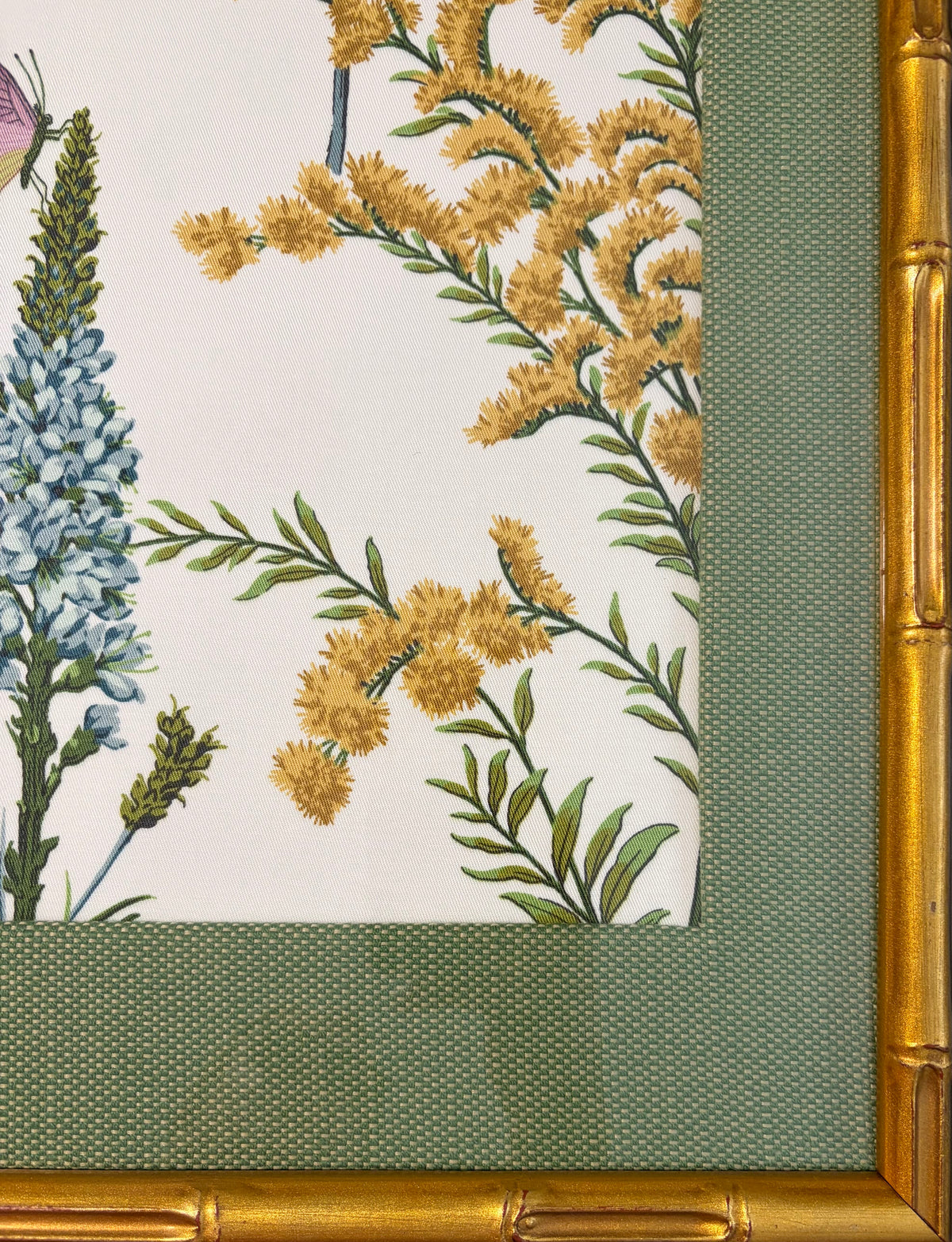Lower-right detail of yellow floral branches with the Callen Green fabric mat and gold bamboo-style frame.