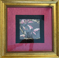 A framed art print featuring a delicate painting of pink and white cherry blossoms on a textured gray background, surrounded by a black inner mat and a vibrant magenta outer mat, all enclosed in an ornate gold frame.