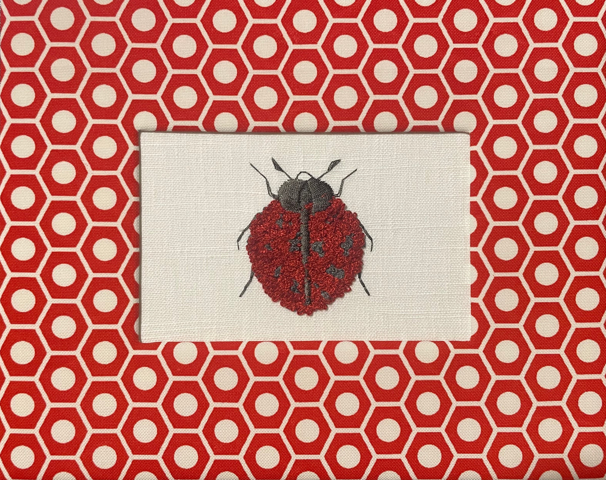 Embroidered Ladybug surrounded by Schumacher Queen B Custom Fabric Mat