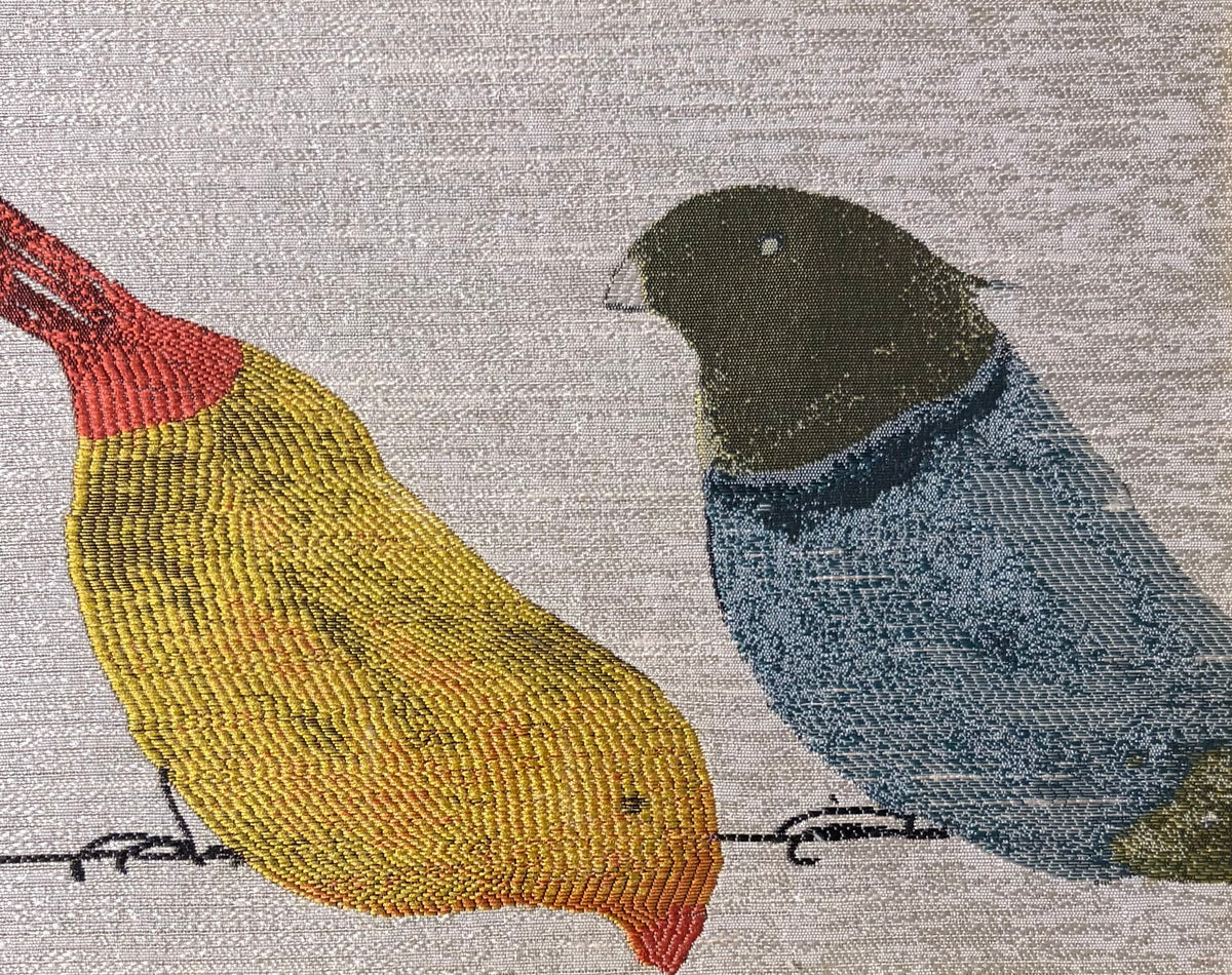 Fabric detail showing the textured yellow bird with red accents beside the blue bird with a dark head.