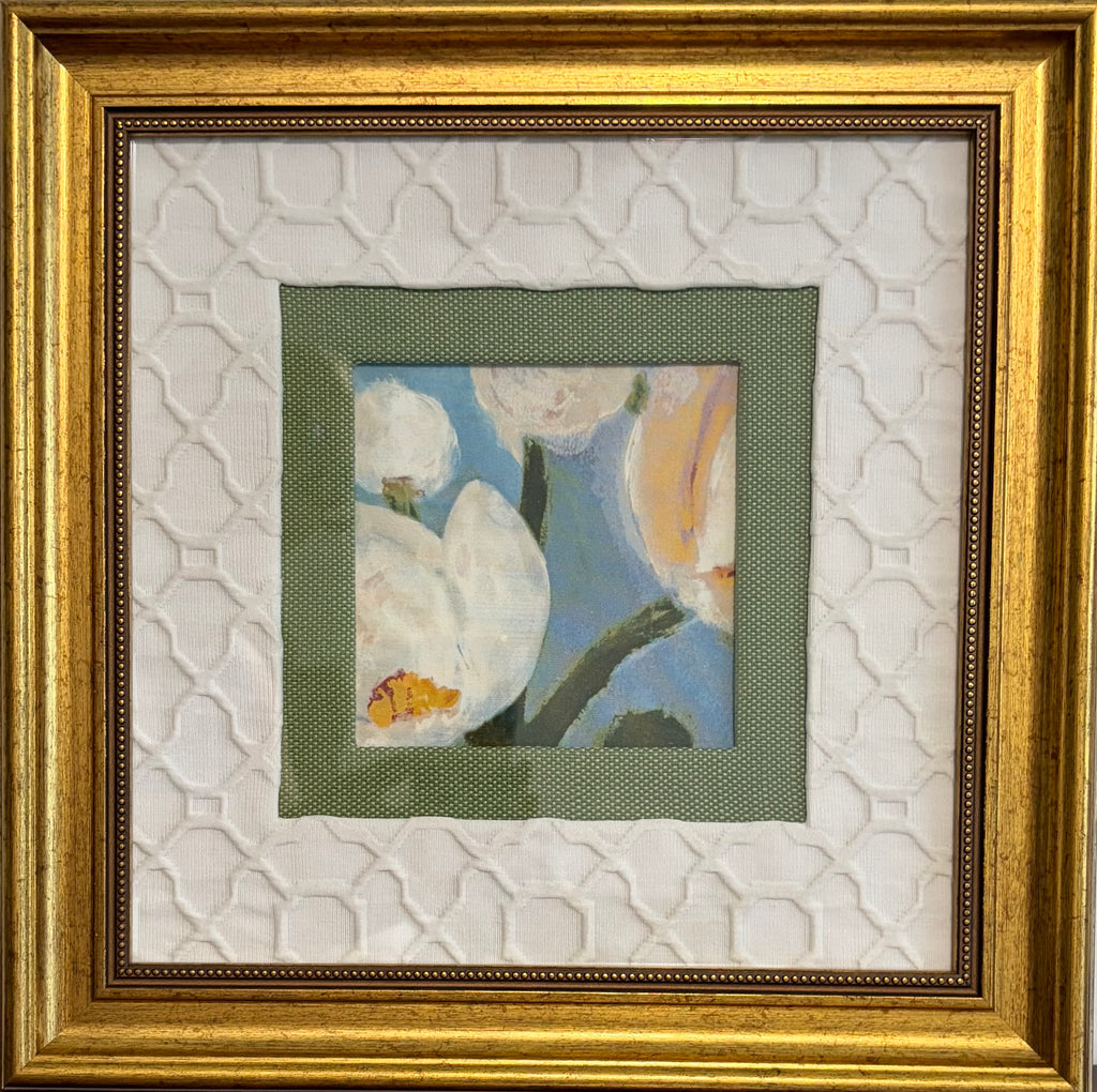 Framed floral artwork with a small central painting of white blossoms and a blue background, surrounded by layered white textured matting and a wide gold frame.