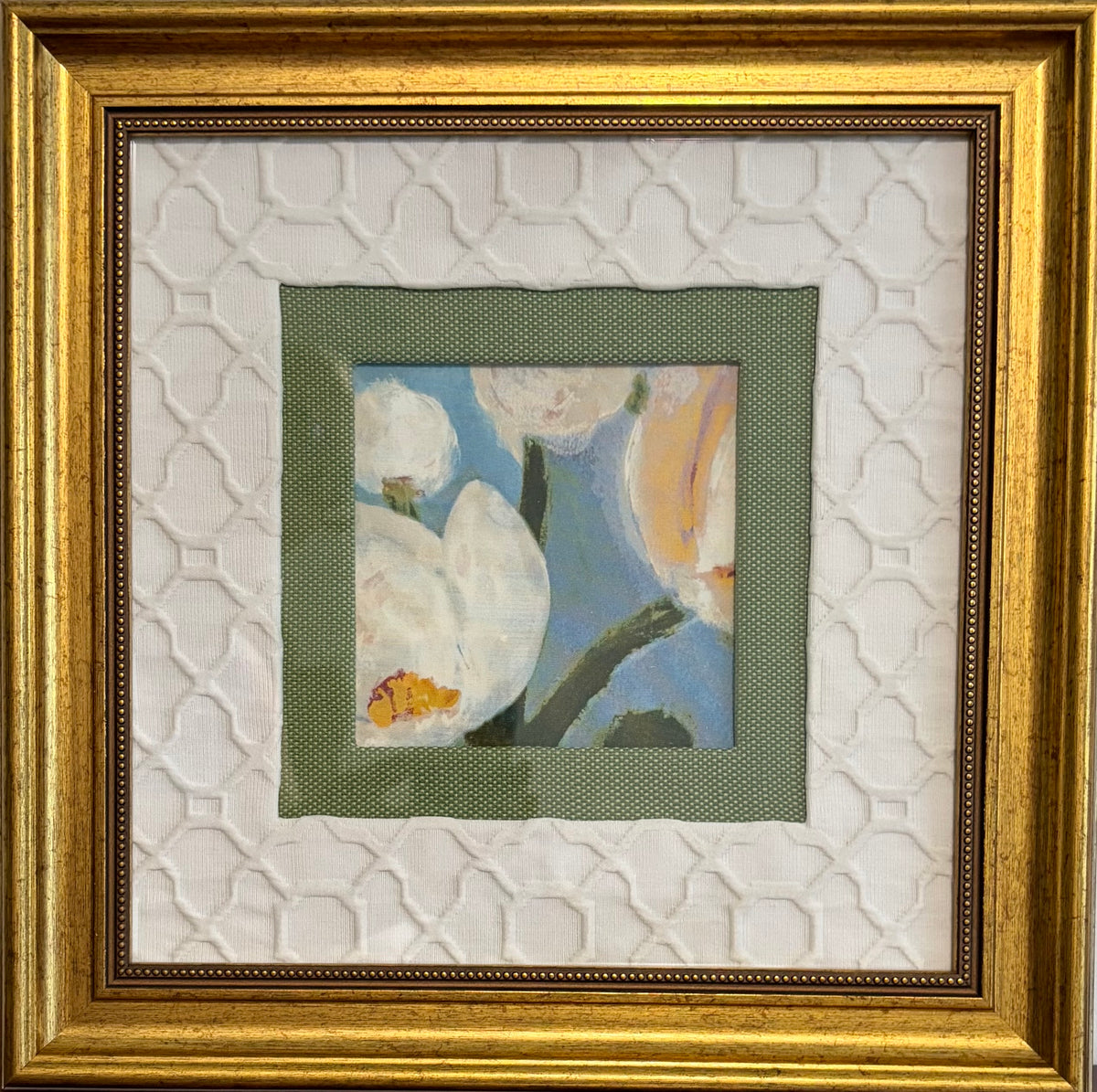 Framed floral artwork with a small central painting of white blossoms and a blue background, surrounded by layered white textured matting and a wide gold frame.